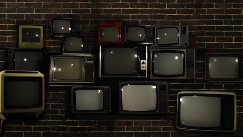 Retro TVs Stacked Against Brick Wall Turning On with Green Screens and Color Bars