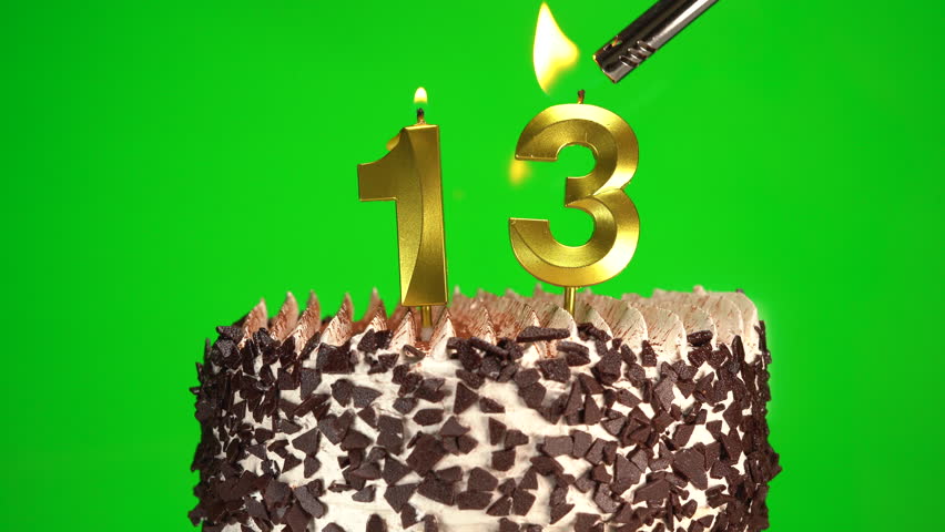 Lighting candles on Chocolate birthday cake on green chroma key background with number thirteen golden candles. Celebration Birthday cake for 13 years. Copy space
