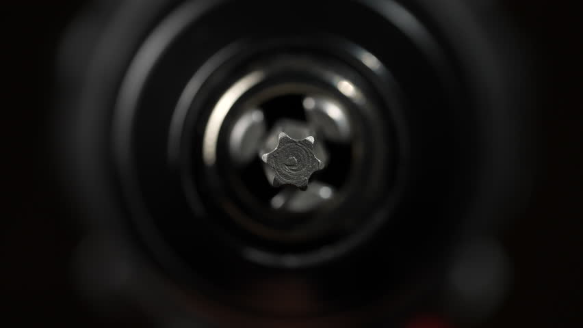 Chuck for cordless screwdriver with rotating torx bit on black background, close up. Nozzle for screwdriver, attachment bit, macro, rotates