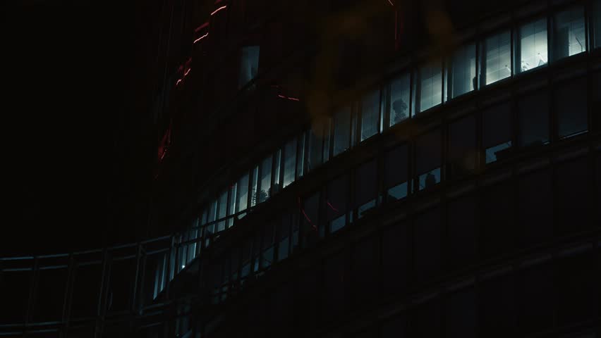 Dimly lit office windows on a curved modern building facade in Zagreb at night
