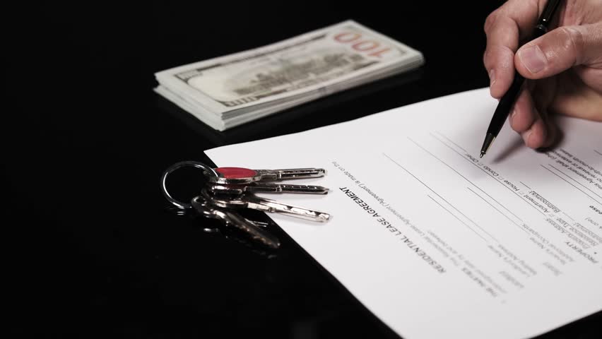 Signing a residential rental agreement with keys and cash – real estate and tenancy concept