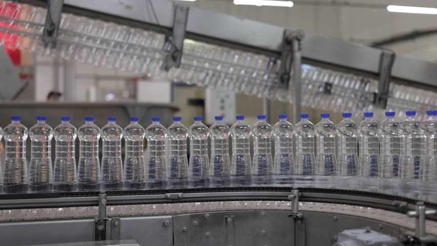 Water bottles on a conveyor belt in a factory. This automated production line shows the manufacturing of plastic bottles.