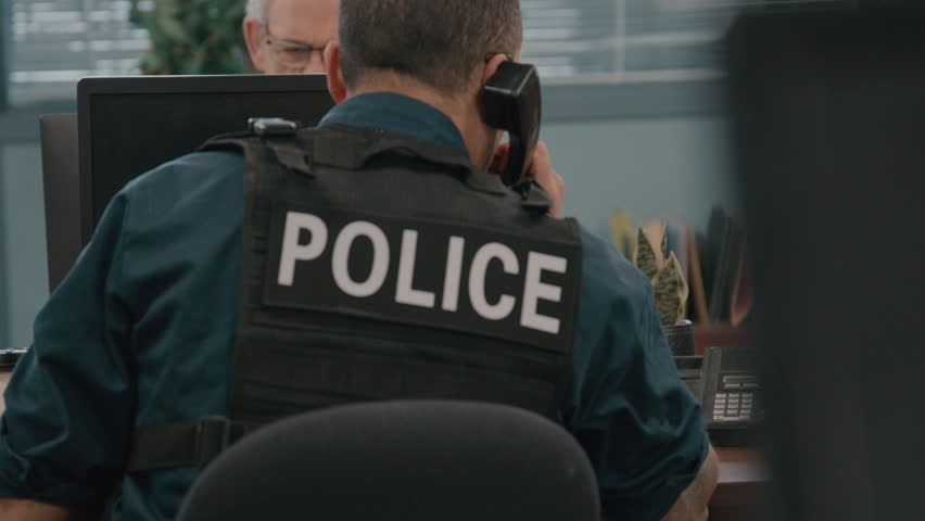 Police officer hanging up phone in precinct