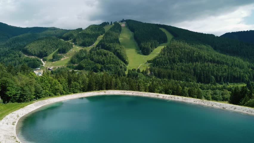 Drone View of Mountain Resort and Lake in Summer. Green Slopes and Forest Landscape