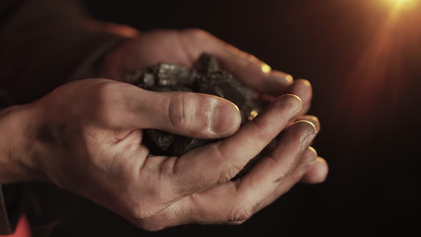 Coal Miner Holding Raw Black Coal in Weathered Hands