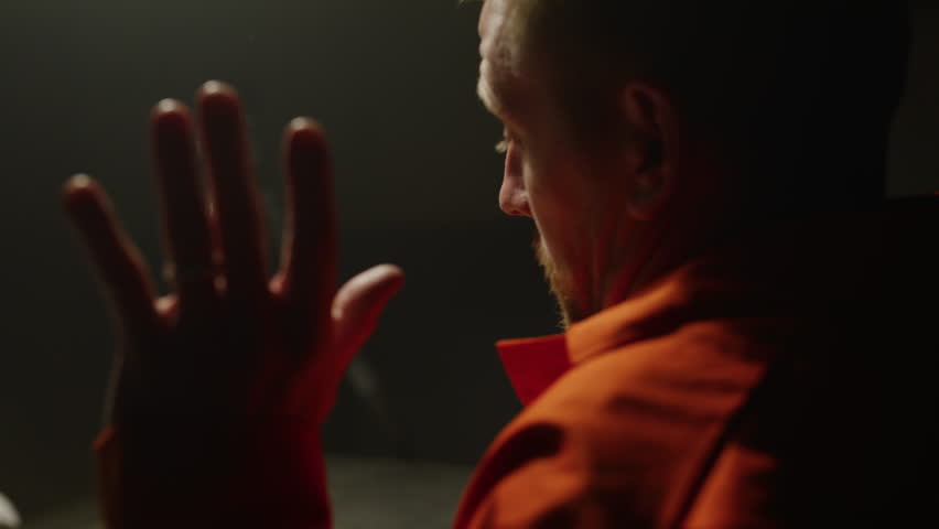Inmate in orange jumpsuit being interrogated on camera caucasian man
