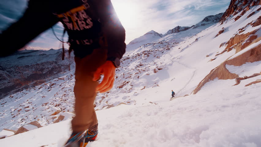 Two climbers navigate a rugged, snow-laden landscape in the Pyrenees of Spain under a bright sky, showcasing the beauty and challenge of high-altitude adventures.
