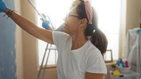 Hispanic couple painting living room together, showcasing teamwork and renovation in their home with a happy woman and man smiling while decorating interior. - Powered by Shutterstock - Get 15% off with code: PIKWIZARD15
