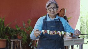 Latin senior woman preparing delicious meat and vegetable barbecue with family - Powered by Shutterstock - Get 15% off with code: PIKWIZARD15