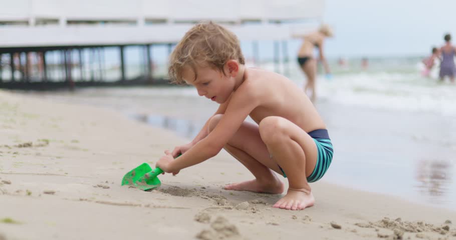 Young boy playing with shovel on beach