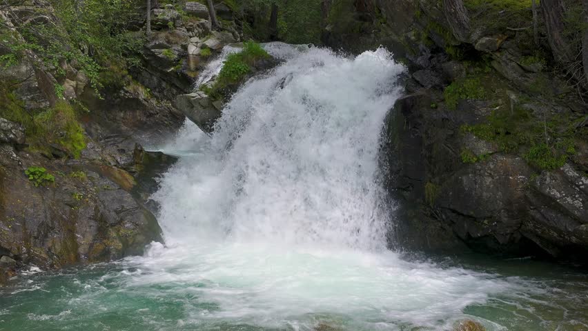 Small waterfall in a mountain stream with crystal-clear water in Alpine nature