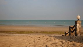 A young woman walks barefoot on the sandy beach, holding a towel. The calm sea and clear sky create a serene and peaceful atmosphere. A woman strolls along the sandy shore, carrying a towel. - Powered by Shutterstock - Get 15% off with code: PIKWIZARD15