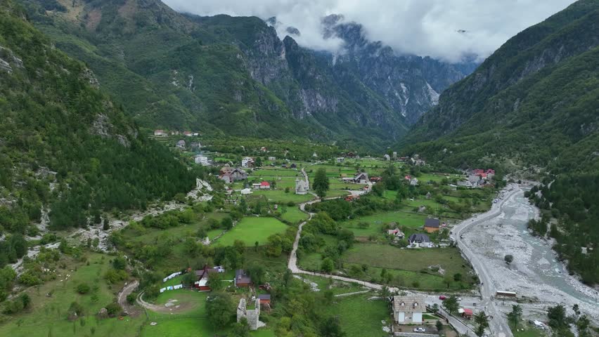 Village of Theth by green mountains in Albania, wide forward aerial