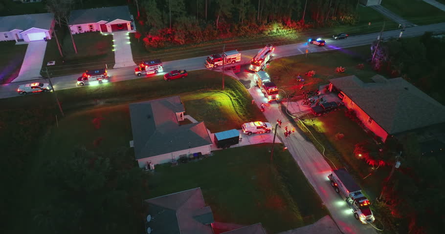 First responders arrived at fire alarm call ready to extinguish fire of burning house at night. Emergency service personnel responding to potential fire hazard at Florida home.