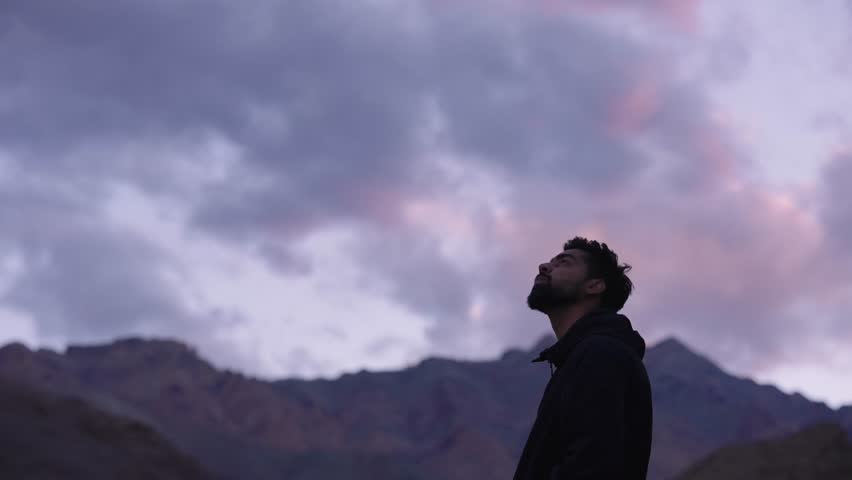 4K footage capturing a magical sunset moment with a person surrounded by towering mountain peaks.