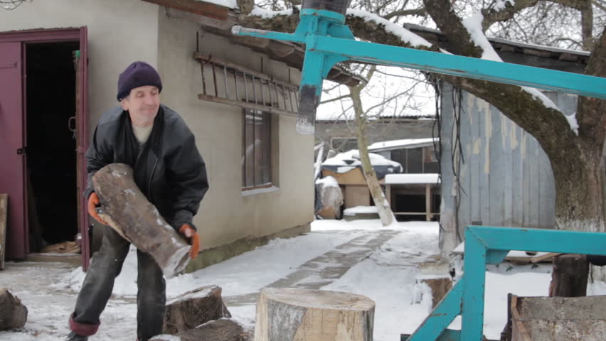 a man chops firewood with a woodcutter, grandfather chopping wood with a mechanical metal wood splitter, wood chopping machine