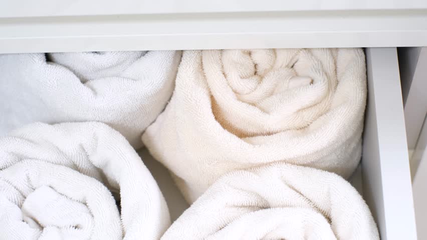 Female hand closing closet with folded towels, concept of space organization.