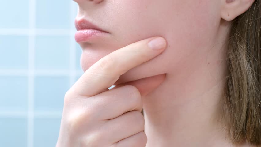 Female face with double chin close-up on blue background, side view.