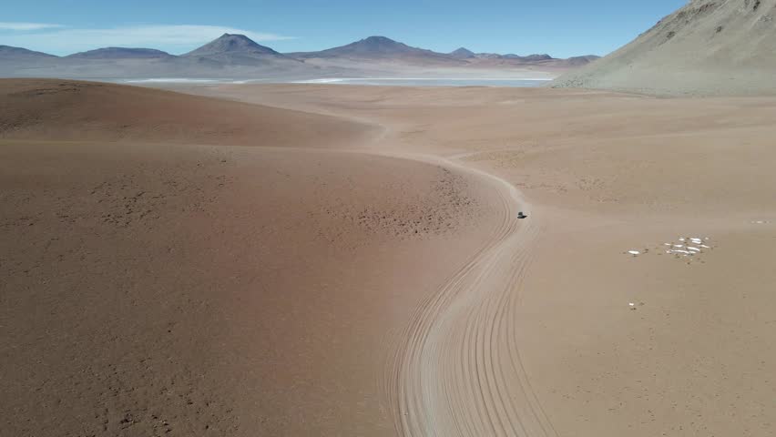 Drone flies along winding road through high desert in Bolivia’s Sud Lipez with distant peaks