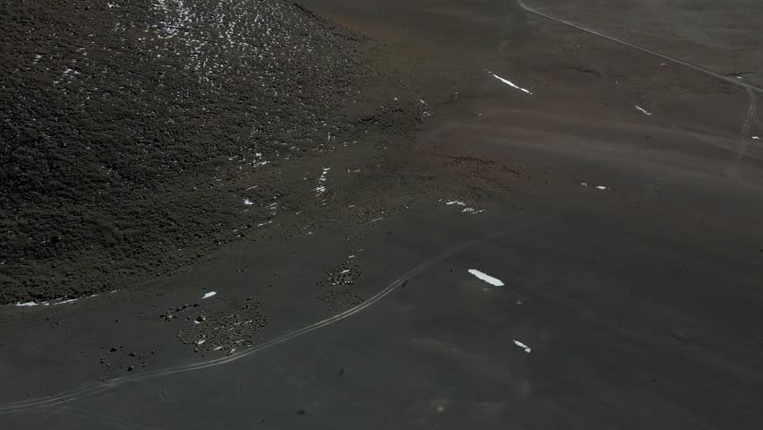 Shadowed aerial of lagoon terrain reveals textures of Bolivia's arid Sud Lipez region