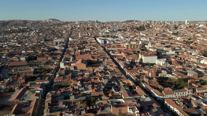 Wide aerial of Sucre, Bolivia showing city grid layout surrounded by green hills and sky