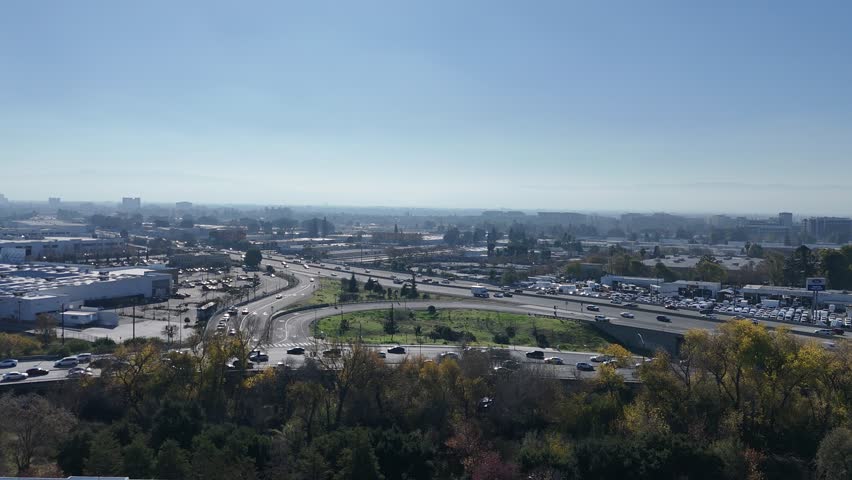 An aerial view of San Jose Freeway, California, USA, showcasing moving cars, winding roads, and the urban landscape in the background
