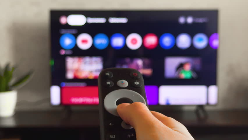 Person watch modern tv pov. Cozy living room large television displaying show, movie, film program. Woman hand holds remote control close up. Home entertainment. First point of view. Streaming service