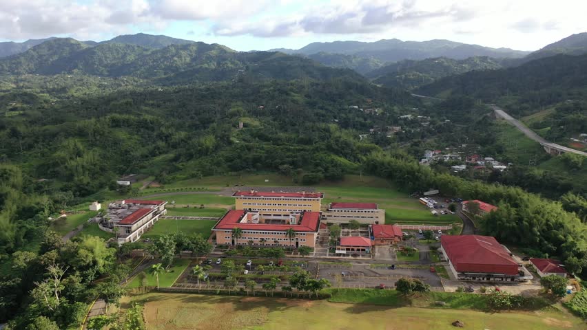 A drone landscape view of UPR - University of Puerto Rico in Utuado surrounded by green spaces and lush hills