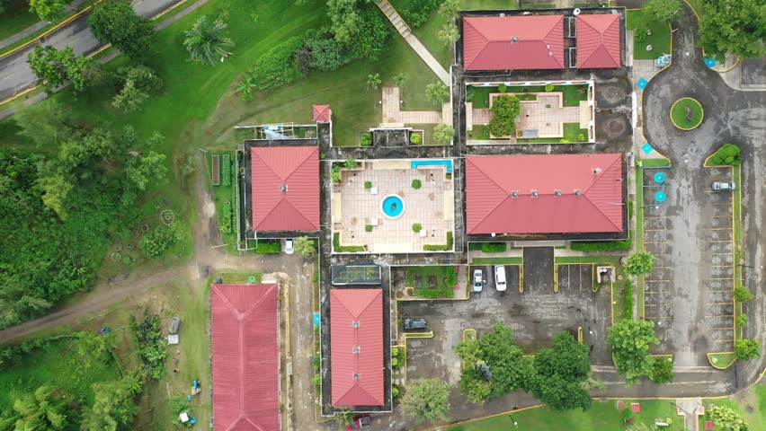A drone top-down view of buildings with brown tiled roofs belong to UPR - University of Puerto Rico in Utuado surrounded by greenery