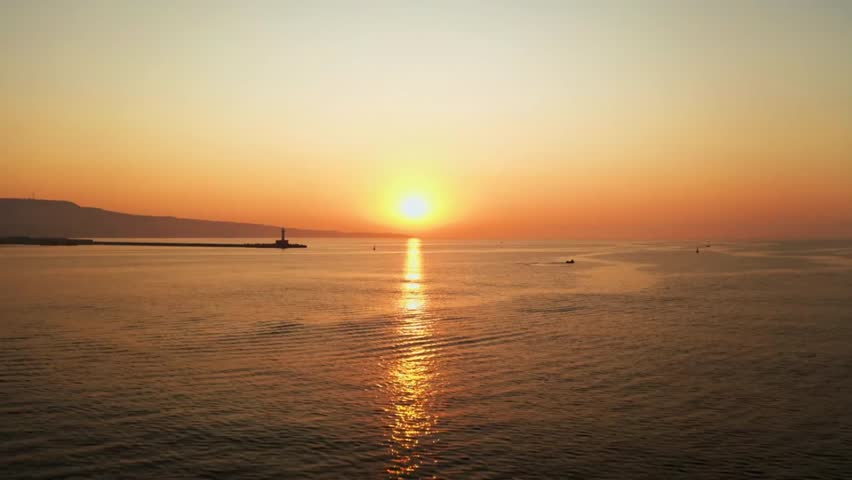 Stunning sunrise over the ocean with a lighthouse silhouetted against the golden light.