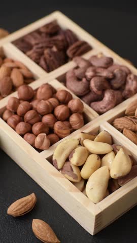 Wooden box with set of different nuts cashew, hazelnut, almond, brazil, pecan, walnut on dark concrete background