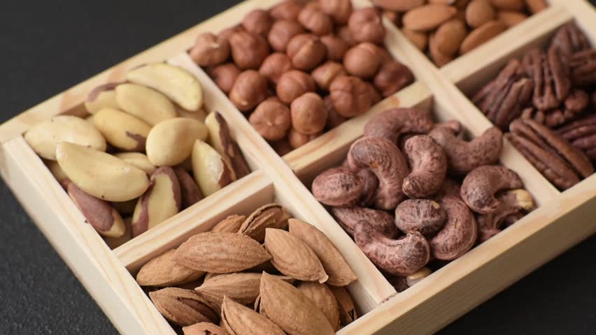 Wooden box with set of different nuts cashew, hazelnut, almond, brazil, pecan, walnut on dark concrete background