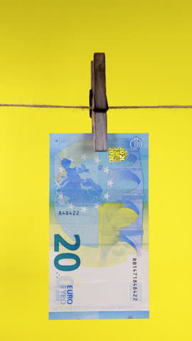 Twenty Euro Banknote Hanging on a Clothesline with Clothespin, 20 euro bill clipped with wooden peg on string against yellow background, concept of money laundering, Vertical footage