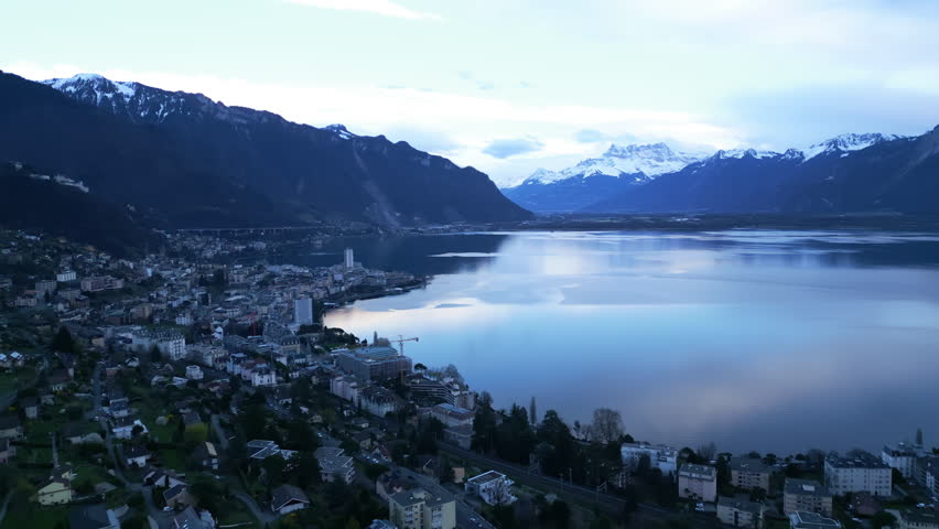 Aerial: Montreux, Dents du Midi and Lake Geneva at sunset in canton of Vaud, Switzerland, establishing drone shot
