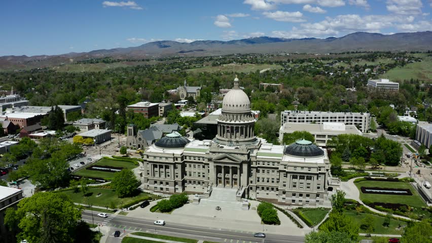 Wide aerial view of the Idaho state capital building surrounded by green trees.