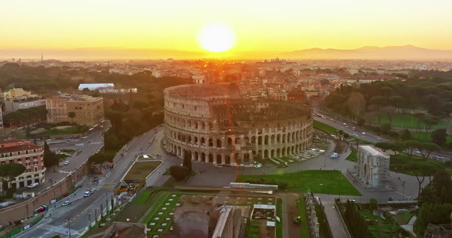 Establishing shot drone flying of the Colosseum. Famous Ancient Roman Arena. Downtown Rome, Italy. The Colosseum and the Imperial Forums in Rome. Beautiful aerial shot with drone around the Colosseum