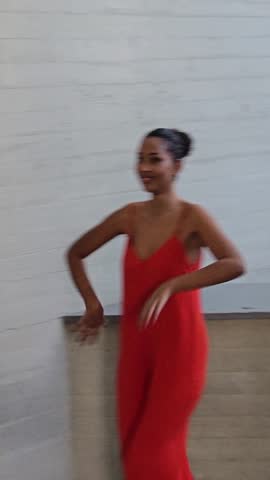 A stylish and fashionable model elegantly poses in a vibrant, eyecatching red outfit against a contemporary, minimalist background, showcasing a perfect blend of modern fashion and timeless grace