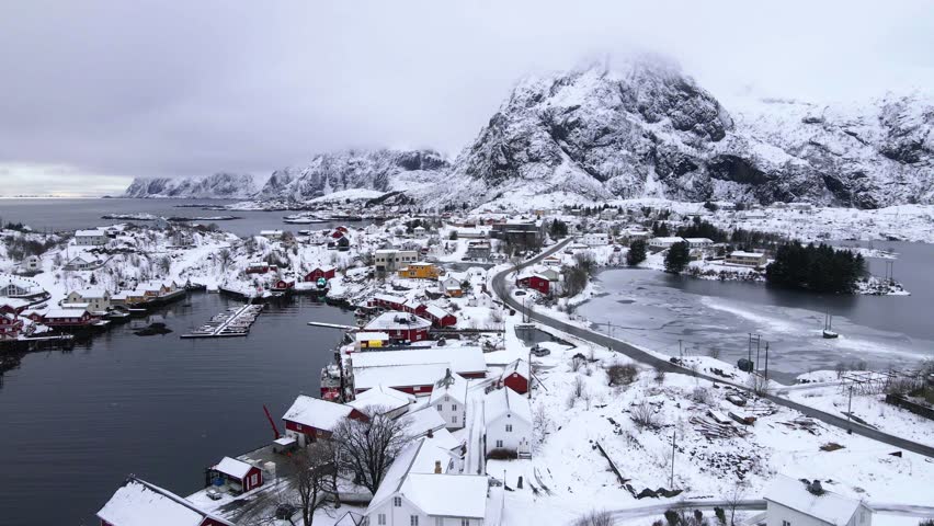 Drone shot flying backwards away form the town of Sørvågen in Lofoten, Norway in winter.