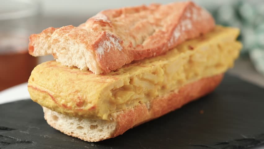  Spanish potato omelette sandwich on wooden table. Bocadillo de tortilla