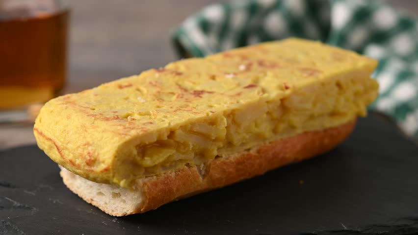  Spanish potato omelette sandwich on wooden table. Bocadillo de tortilla