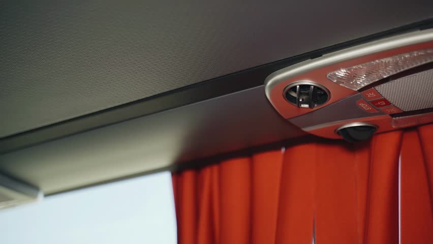 A close look at the advanced air-conditioning and lighting control system positioned above the passenger seat in the bus.