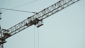 Metal trolley on wheels moves on boom of tower crane. Trolley for transporting construction materials moves during operation of tower crane on construction site against sky. - Powered by Shutterstock - Get 15% off with code: PIKWIZARD15