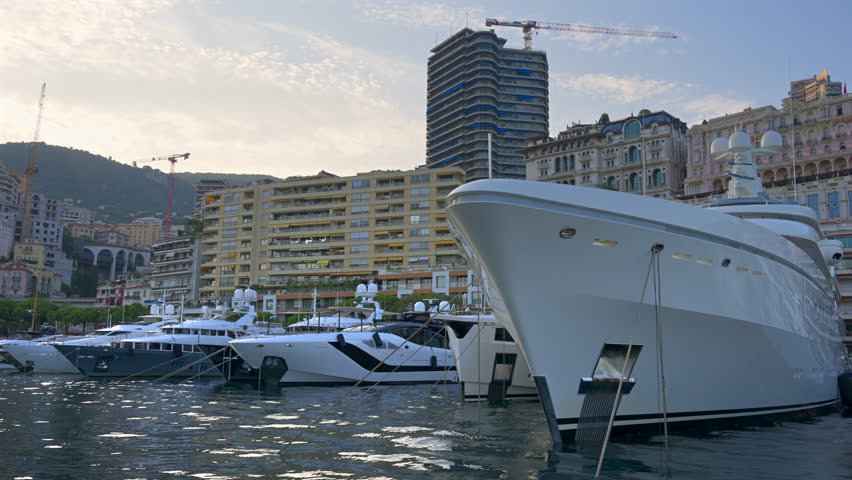 La Condamine, Monaco - August 25, 2024: Close up of multiple boats docked in Port Hercules with the skyline of the city on the background at sunset
