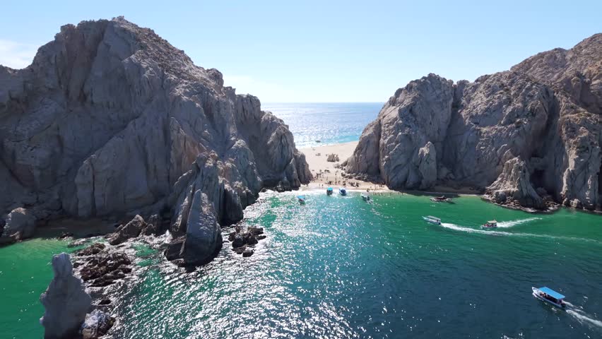Aerial pass in Cabo San Lucas through Lover's Beach known over rock formation to Divorce beach in the Pacific Ocean