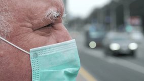 Senior man wearing protective face mask standing by busy road. Men observing traffic flow with focused expression during pandemic urban environment, representing health safety precautions - Powered by Shutterstock - Get 15% off with code: PIKWIZARD15