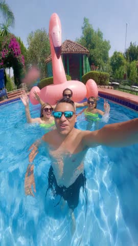 Friends taking a selfie while waving in a swimming pool