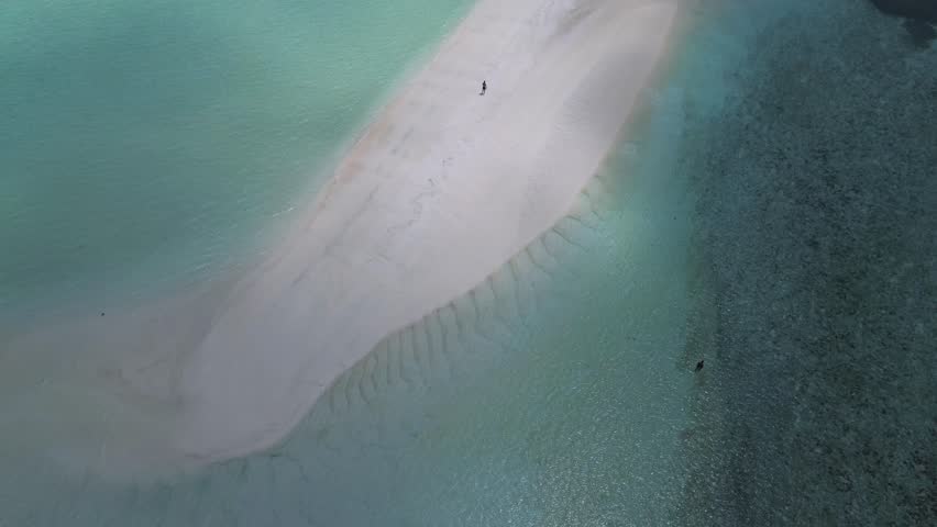 Aerial view of beautiful Maldives island with white sandy beach at sunny day.Drone point of view video.Two people walking on sandbank.Thulusdhoo.Maldives