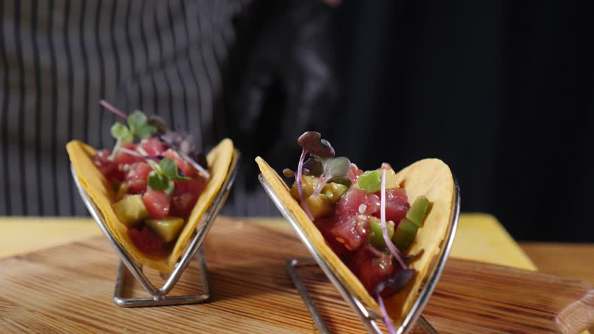 Traditional Mexican food. Chef in black gloves cooking delicious vegetarian tacos adding micro greens. Slow motion. cold snacks in restaurant. symbolizing Mexican cuisine and street food culture. Full