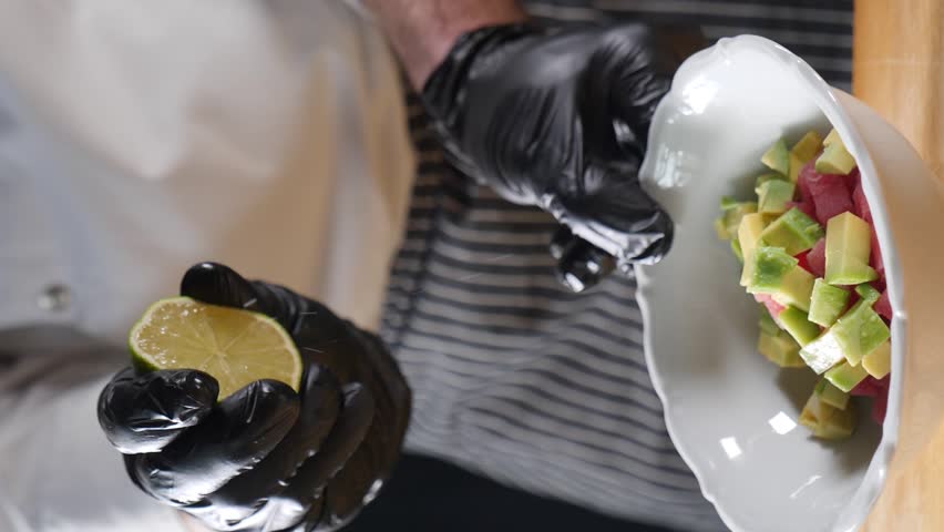 Squeezing lime juice with splashes into a vegeterian salad dish. Slow motion food video. Organic citrus juice close-up. chef cooking in restaurant . Full hd