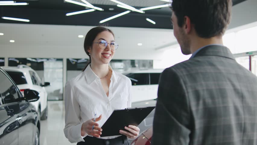 Sales representative discusses features and financing options with a potential buyer at a modern car dealership showroom